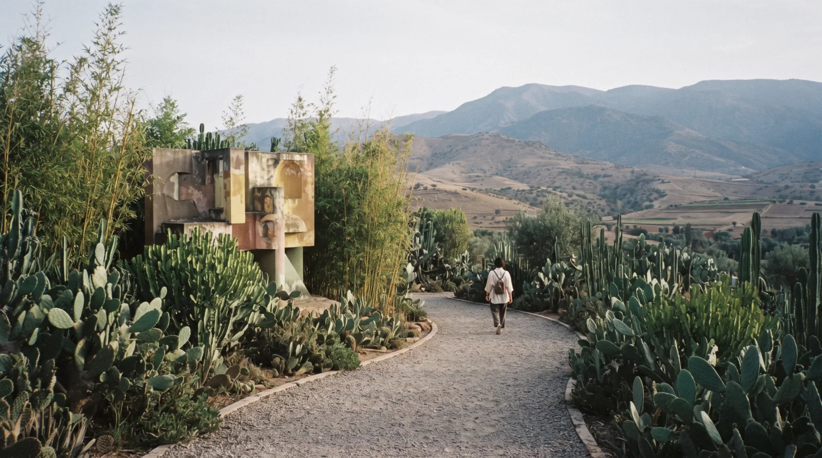 Sculpture standing among cactus and palms with the Atlas foothills behind, ANIMA Garden on the Ourika road outside Marrakech