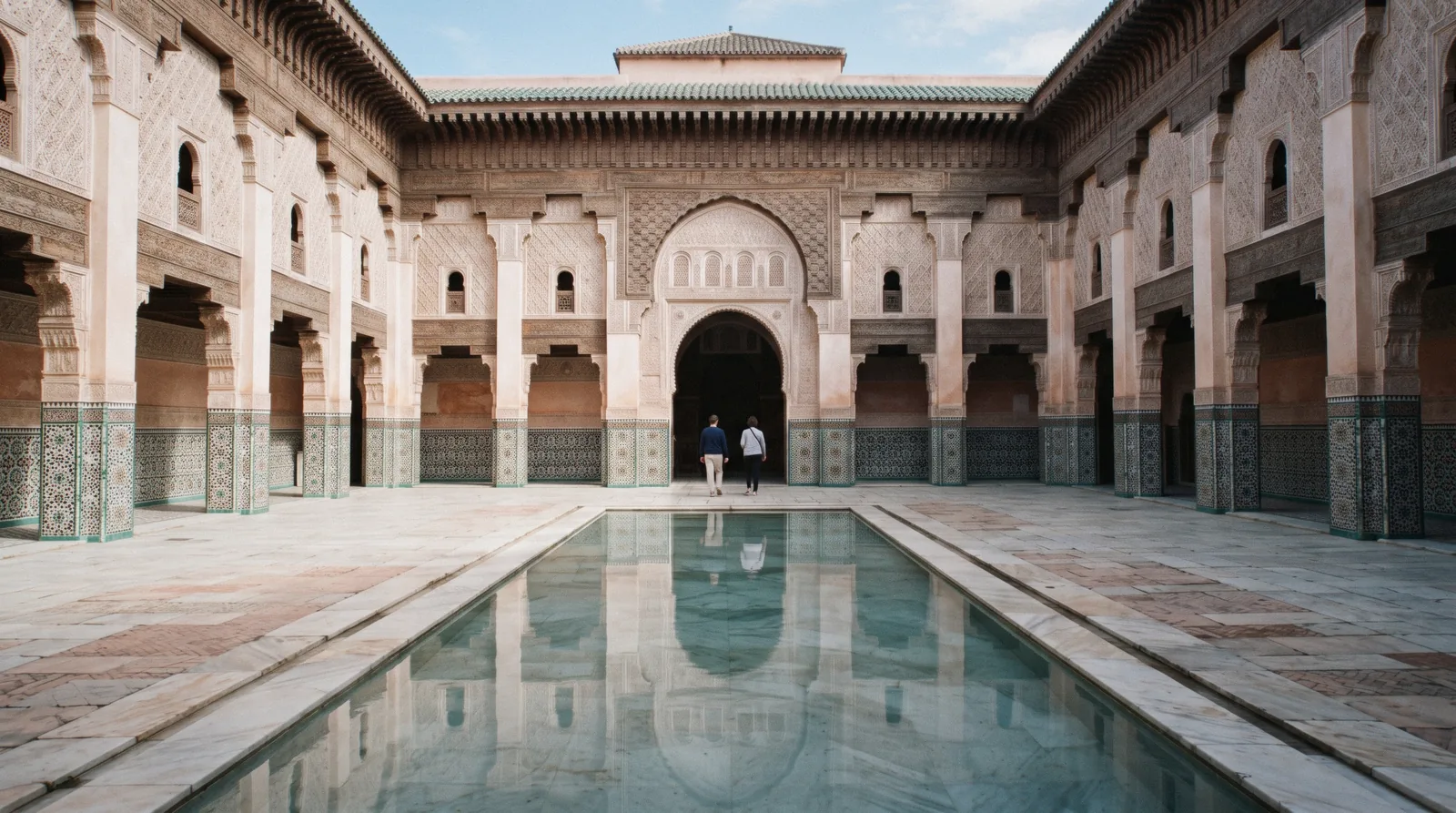 Zellige courtyard and reflective pool ringed by carved cedar galleries at the Ben Youssef Madrasa, Marrakech