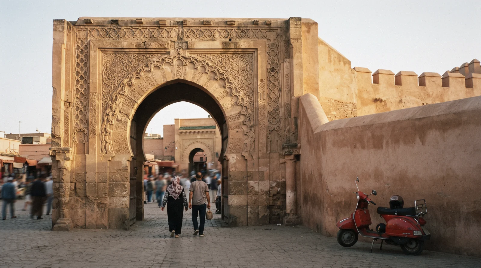 The carved sandstone horseshoe arch of Bab Agnaou in low sun with the rampart running east, Kasbah Marrakech