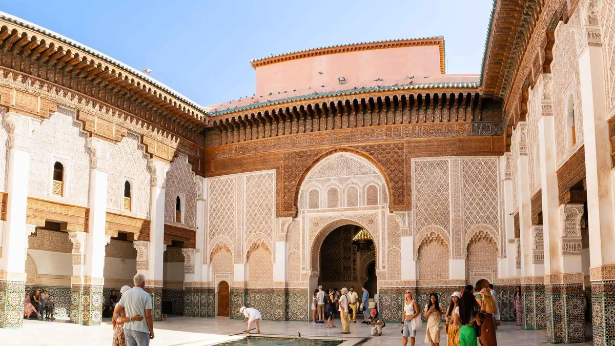 Guide leading visitors past a fondouk doorway in the old medina on a Marrakech medina and historical monuments guided tour