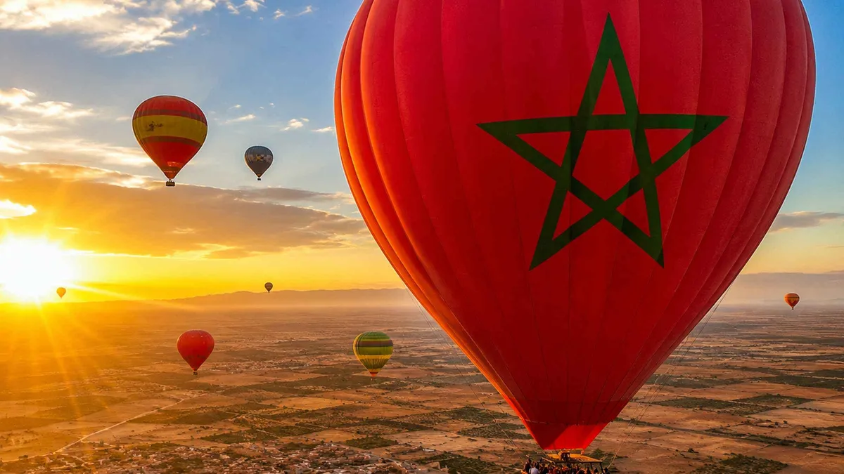 Balloon basket rising over palm groves and the Atlas skyline on a Marrakech hot air balloon ride with Berber breakfast