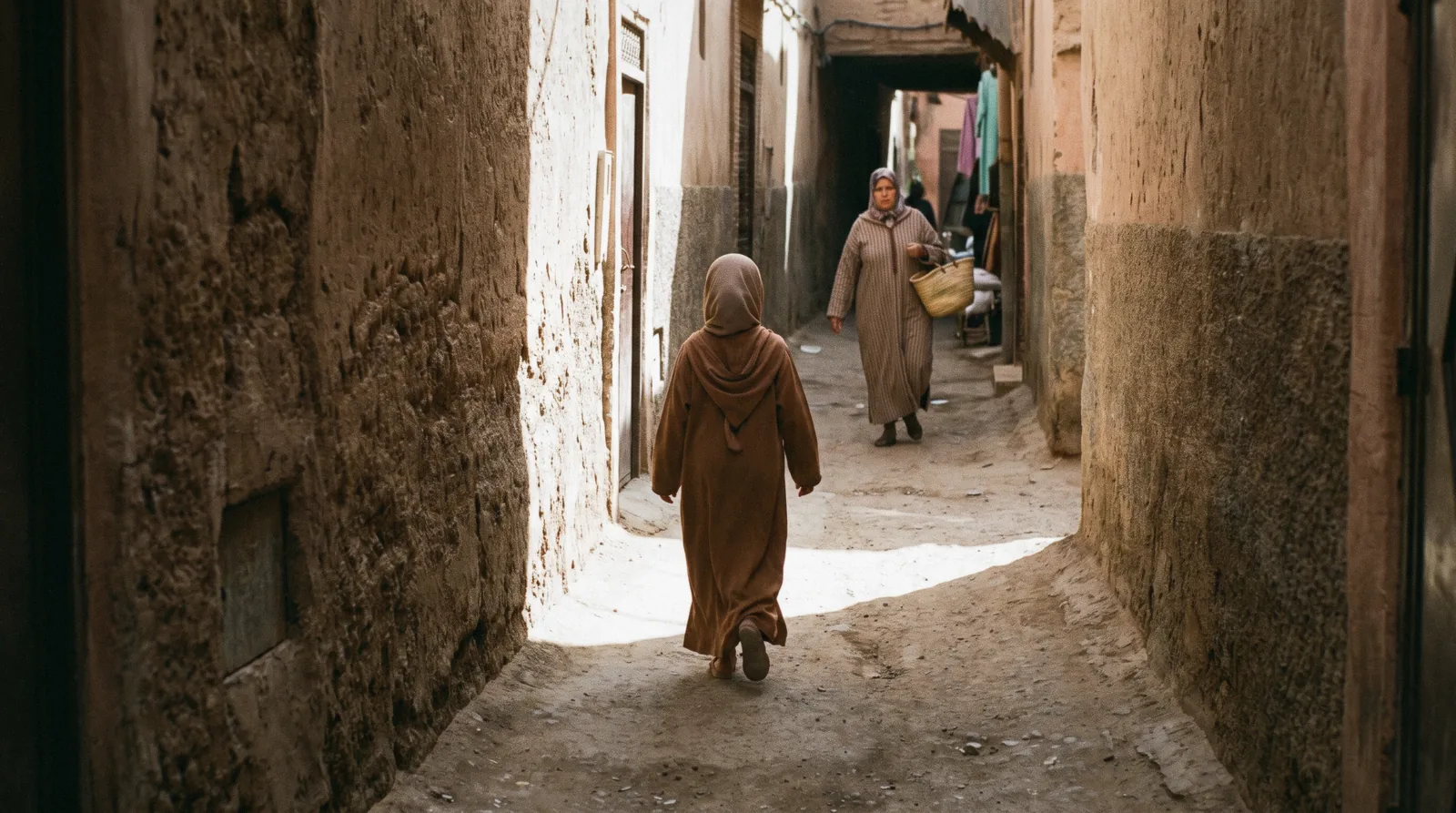 Shoppers in loose linen and long sleeves passing a dyers' lane in the souks, the everyday answer to what to wear in Marrakech