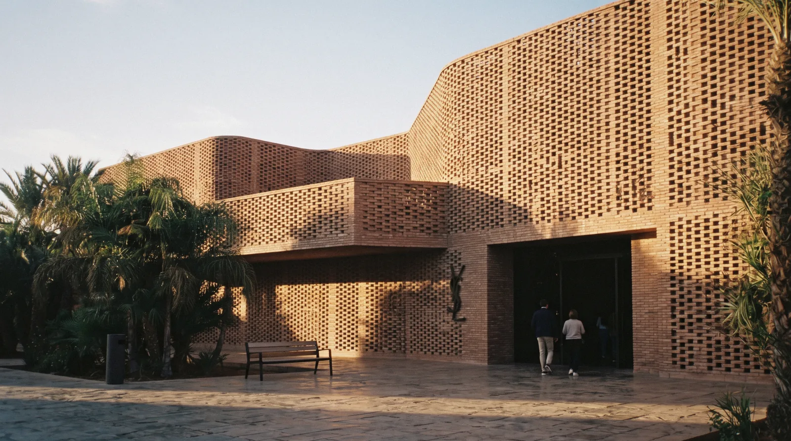 Terracotta brick lattice facade of the YSL Museum Marrakech in low afternoon sun on Rue Yves Saint Laurent